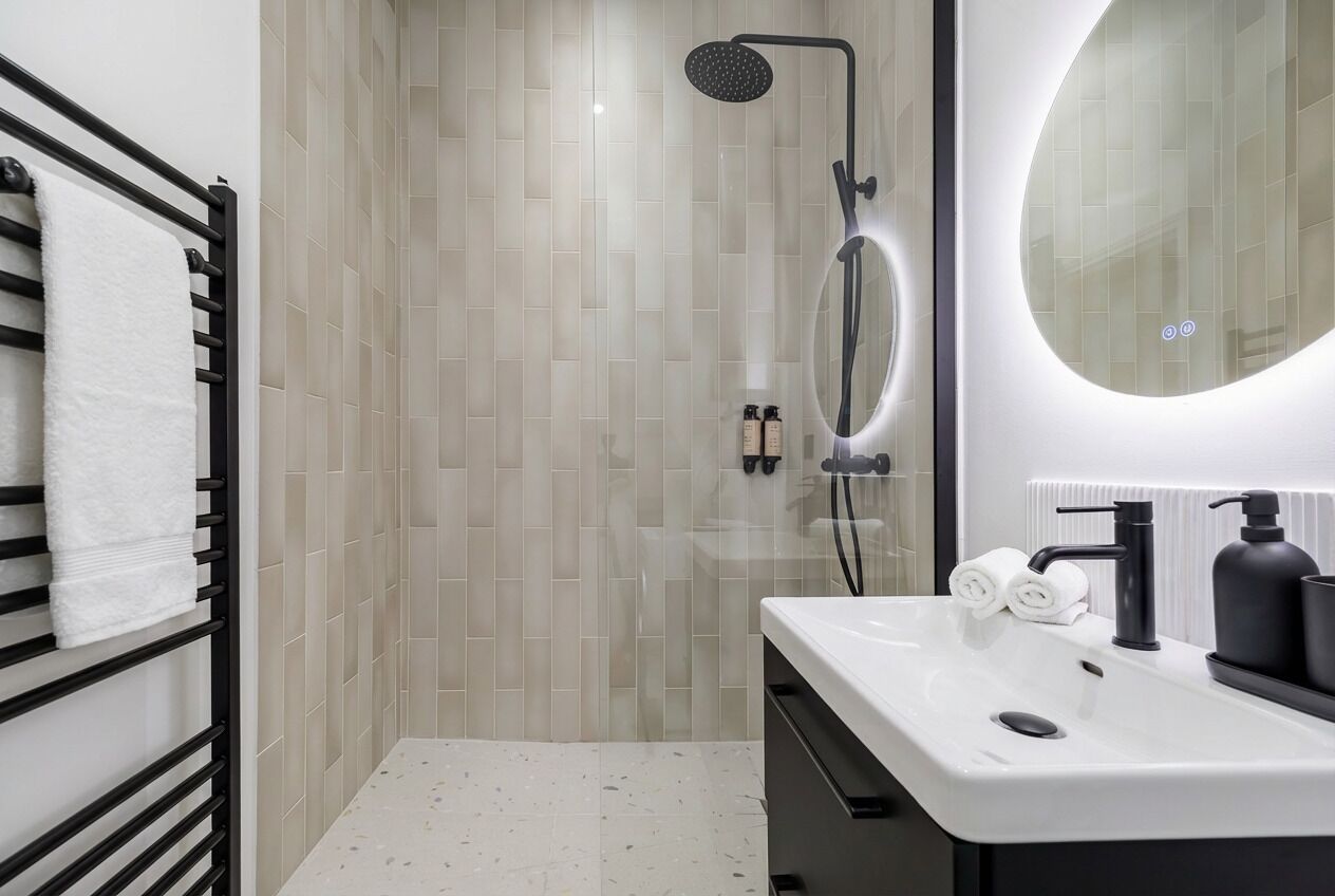 A modern bathroom with a shower, a sink, and a towel rack.