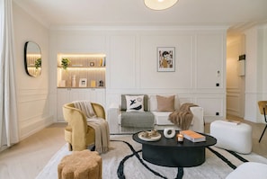 Een moderne woonkamer met een bank, fauteuil, salontafel en een decoratieve wandmeubel.