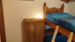 Ett sovrum med en våningssäng, ett nattduksbord, en garderob och en luftkonditioneringsanläggning.