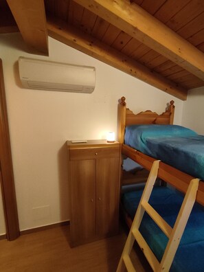 Una camera da letto con un letto a castello, un comodino, un armadio e un condizionatore d'aria.