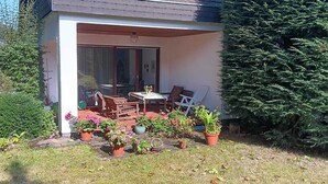 Um pátio com móveis de exterior, porta de vidro e vasos de plantas.