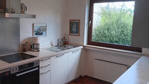 Uma cozinha moderna com forno embutido, cafeteira e janela com vista para o verde.