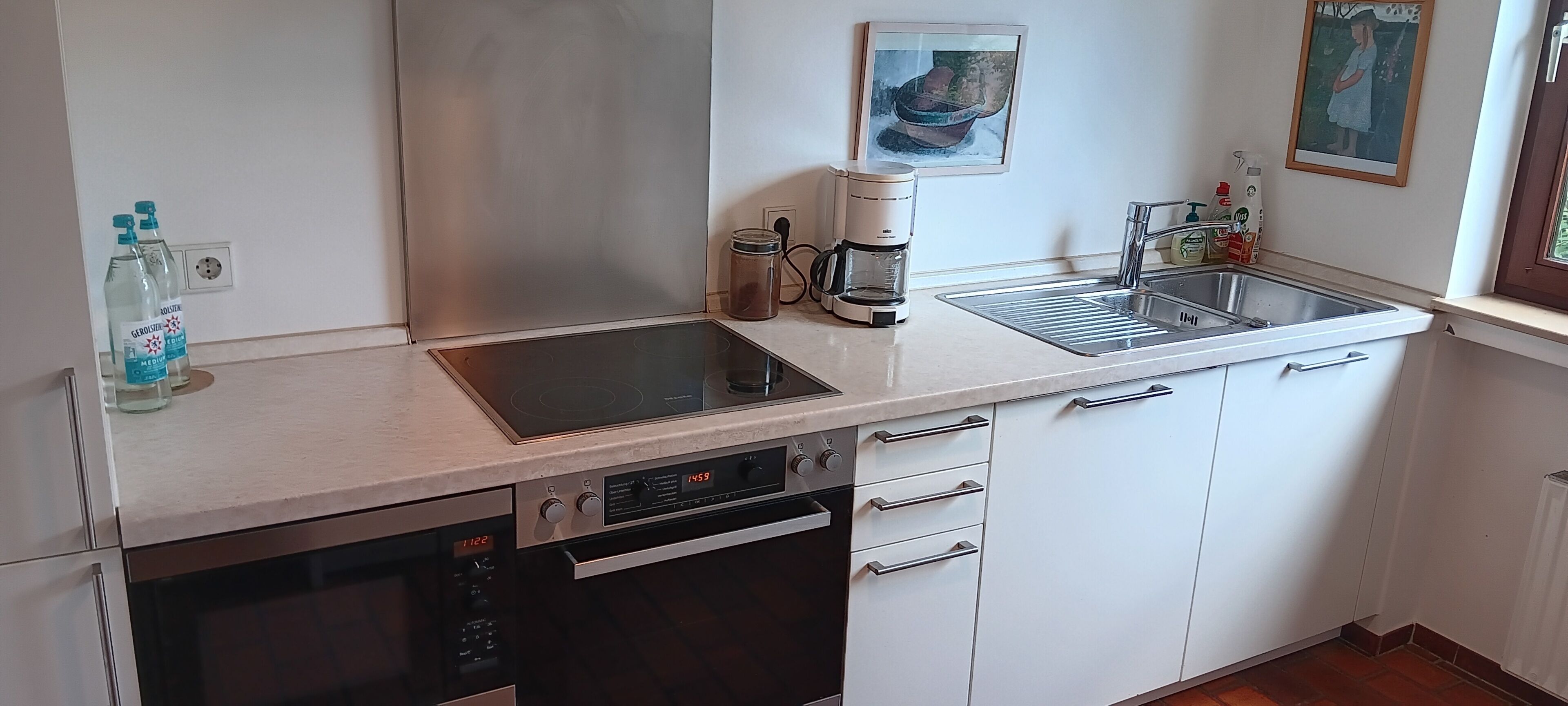 Een moderne keuken met een vaatwasser, oven en koffiezetapparaat op het aanrecht.