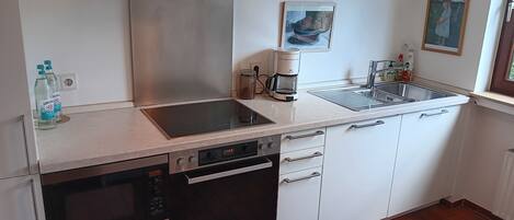 A modern kitchen with a dishwasher, oven, and a coffee maker on the counter.
