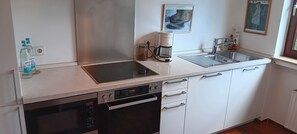 Une cuisine moderne équipée d’un lave-vaisselle, d’un four et d’une machine à café posée sur le plan de travail.