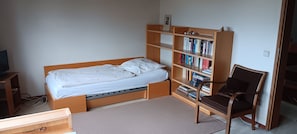Ein Schlafzimmer mit Bett, Bücherregal, Stuhl und Schreibtisch.
