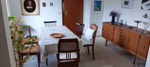 Ein Essbereich mit Tisch, Stühlen, einem Schrank und einer Topfpflanze.