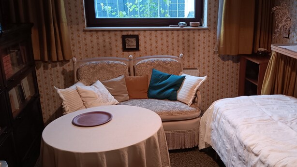 Um quarto aconchegante com uma cama, uma mesa pequena e uma janela com vista para o verde.