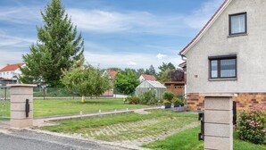 En bostadsgata med hus, en gräsyta och en klar himmel.