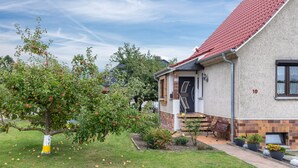 En bostadsbyggnad med ett rött tegeltak, en fasad av tegel och en välskött trädgård med äppelträd.