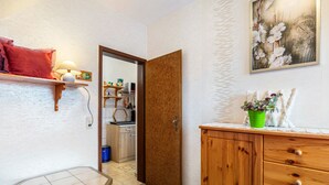 En hall med ett träskåp, ett litet bord och en dörr som leder in till ett kök.