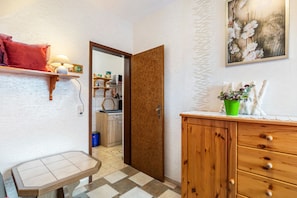 Un pasillo con un armario de madera, una mesita y una puerta que da a una cocina.