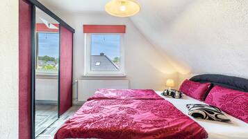 Une chambre avec un grand lit, une fenêtre donnant sur un beau paysage et un luminaire au plafond.