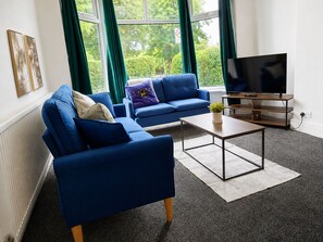 A modern living room with a blue sofa, a coffee table, and a TV.