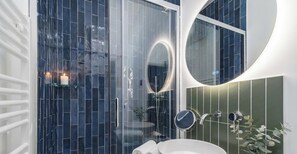 A modern bathroom with a glass shower enclosure, a round mirror, and a white sink. - PoeticStay - Opéra - Hanovre (Paris)