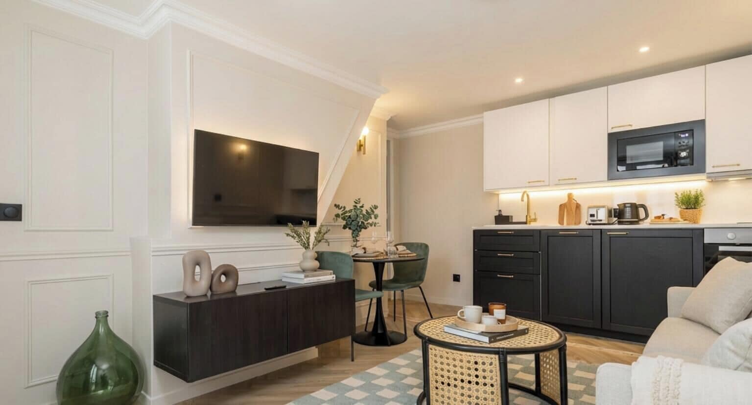Una sala de estar moderna con un mueble bajo de madera oscura, un televisor de pantalla plana montado en la pared, una mesa de centro redonda y un sofá.