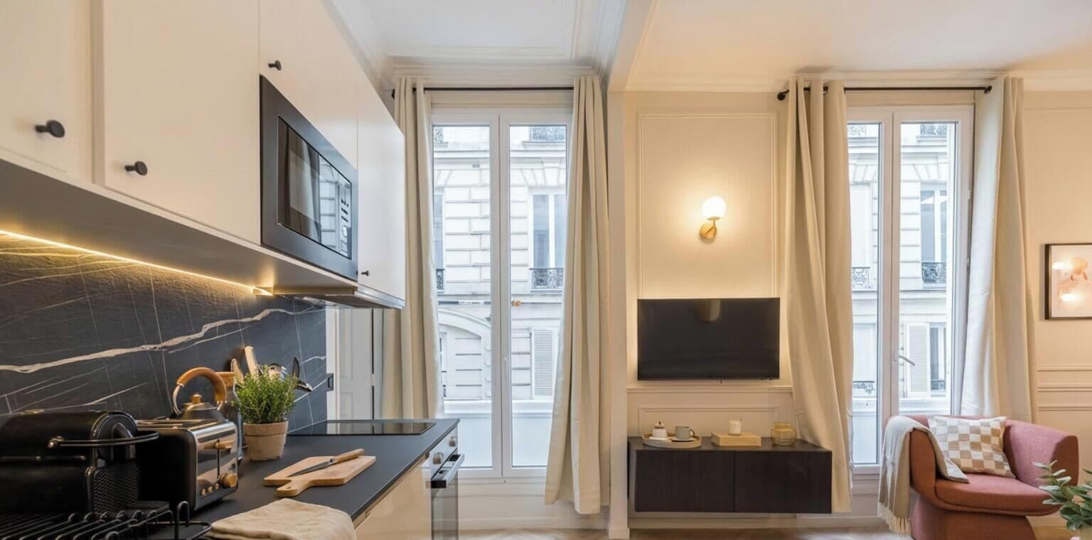 Una cocina moderna con protector de encimera de mármol negro, horno empotrado y televisor de pantalla plana montado sobre la encimera.