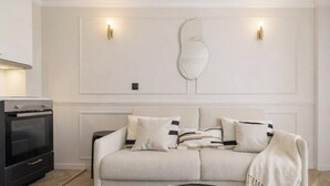 A living room with a sofa, a decorative mirror, and wall-mounted lighting.
