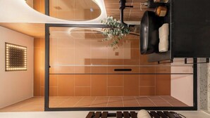 A modern bathroom with a glass shower enclosure, a wooden bench, and a towel rack.