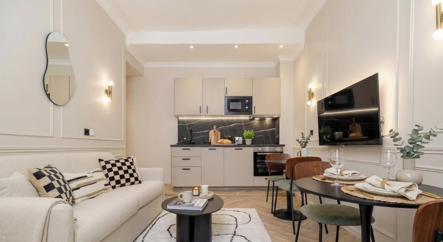 Una sala de estar moderna con sofá, mesa de centro y comedor con sillas y una mesa dispuesta para una comida.