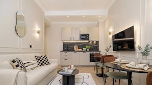 A modern living room with a sofa, coffee table, and dining area with chairs and a table set for a meal.