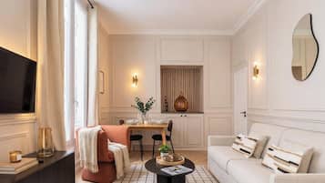 Uma sala de estar com sofá, mesa de centro, TV e área de jantar com mesa e cadeiras.