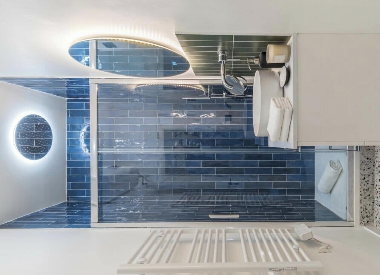Un baño moderno con cabina de ducha de vidrio, lavamanos empotrado y un perchero para toallas.