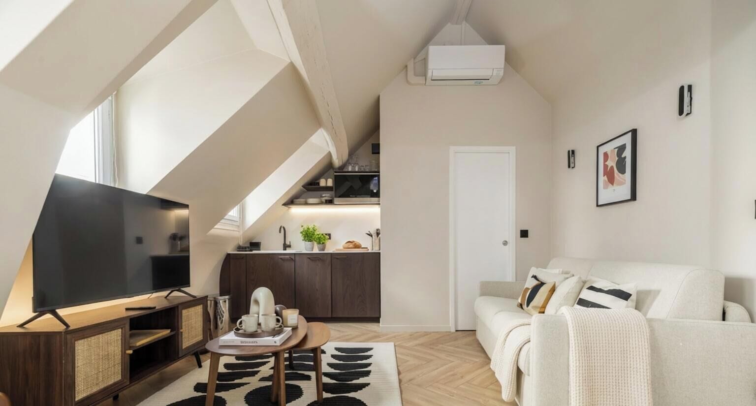 Een moderne woonkamer met een flatscreen televisie, een bank en een eethoek met een tafel en stoelen.