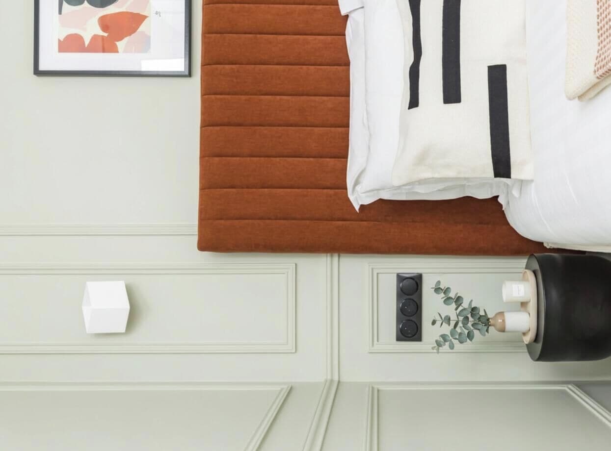 A neatly made bed with a brown headboard, a white pillow, and a white pillowcase.