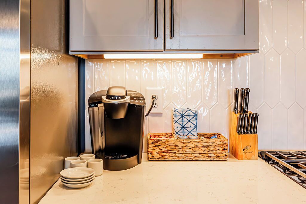 Une cuisine équipée d’une machine à café, d’un bloc à couteaux et d’un panier en osier.