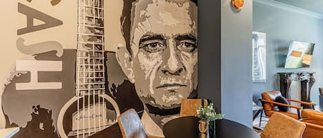 Een modern interieur met een grote muurschildering, een ronde tafel met stoelen en een klok aan de muur.