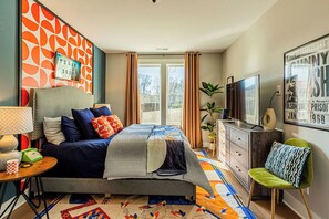 A bedroom with a bed, a television, a desk with a lamp, and a chair. - Johnny Cash's Ring of Fire Retreat: Rooftop Deck (Nashville)