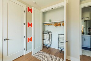 A hallway with a patterned rug, a coat rack, and a laundry cart. - Johnny Cash's Ring of Fire Retreat: Rooftop Deck (Nashville)