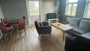 Ein Wohnzimmer mit Holzboden, einer Couch, einem Couchtisch und einem Fernseher.