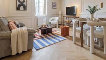 Uma sala de estar com sofá, poltrona, mesa de centro e um canto de jantar com cadeiras e mesa.