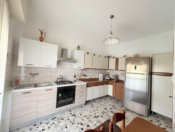 A kitchen with white cabinets, a stainless steel refrigerator, a gas stove, and a coffee maker.