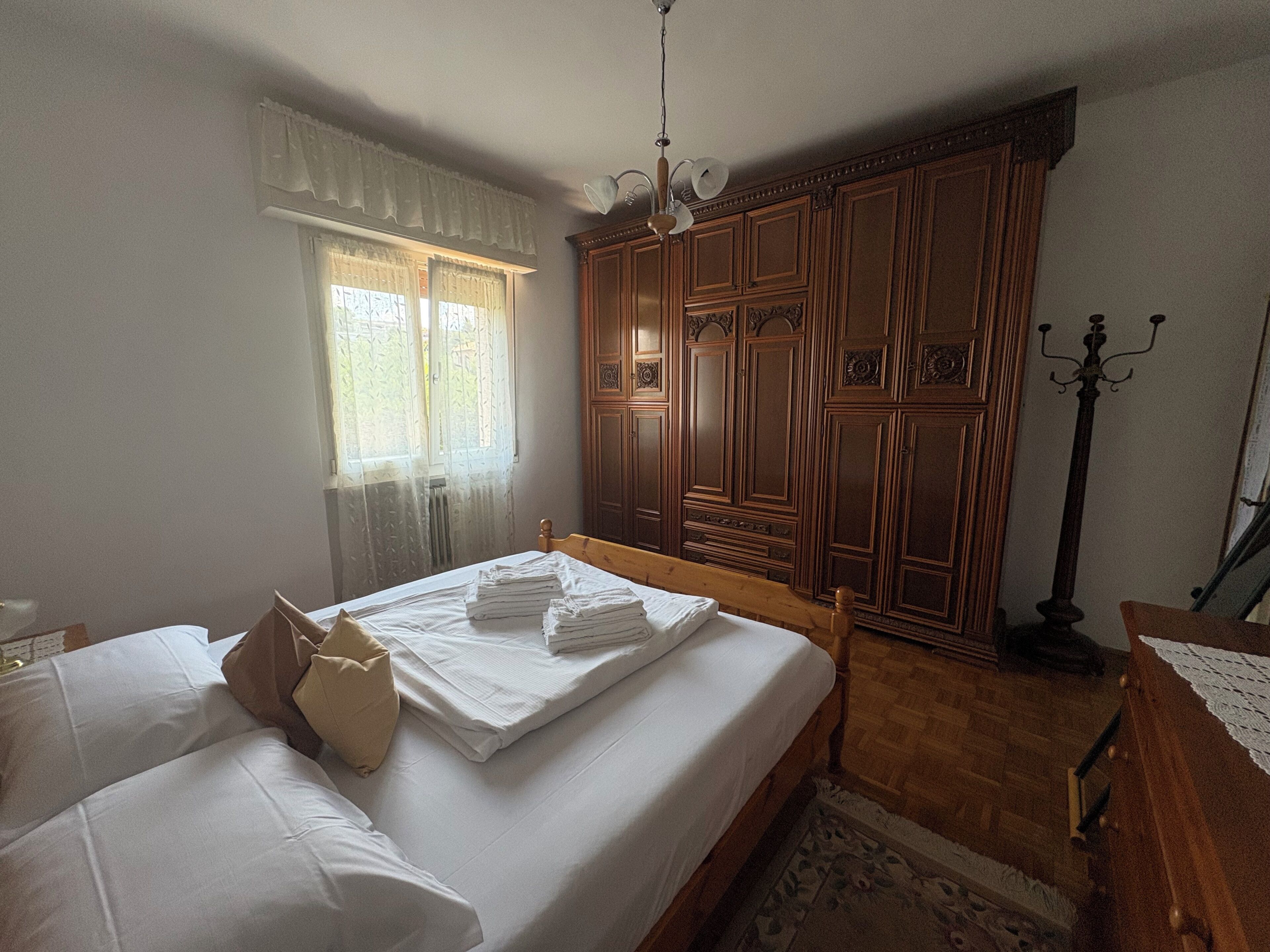 Une chambre à coucher avec un lit, une armoire, une fenêtre avec des rideaux et une lampe de sol.