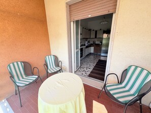 A patio with two striped chairs and a round table, leading to a kitchen area with a refrigerator and cabinets. - Two-bedroom apartment on the first floor, just a few minutes' walk from downtown (Bardolino)