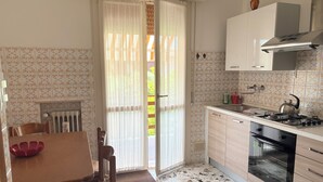 A kitchen with a dining table, chairs, a stove, oven, and a window with curtains.