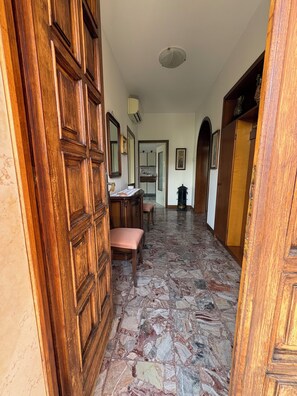 A hallway with a wooden door, a bench, a table with papers, and a tiled floor. - Two-bedroom apartment on the first floor, just a few minutes' walk from downtown (Bardolino)