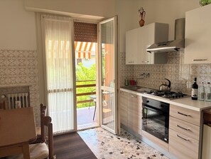 A kitchen with a gas stove, oven, and a dining area with a table and chairs. - Two-bedroom apartment on the first floor, just a short walk from downtown (Bardolino)