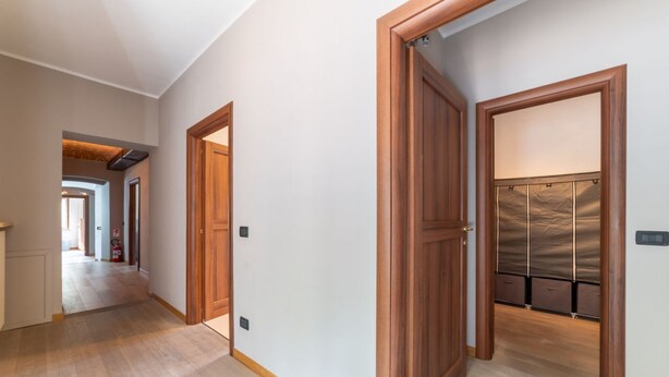 A hallway with wooden doors and a coat rack with hanging items.
