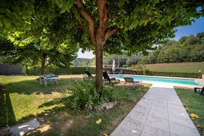 A backyard with a swimming pool, lounge chairs, and a paved walkway. - Exclusive Villa with Swimming Pool and Tennis Area (Frinco)