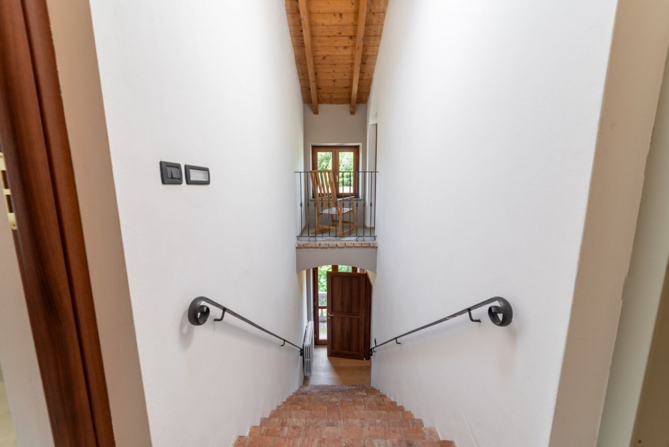 A staircase with a wooden ceiling and a view of a balcony.