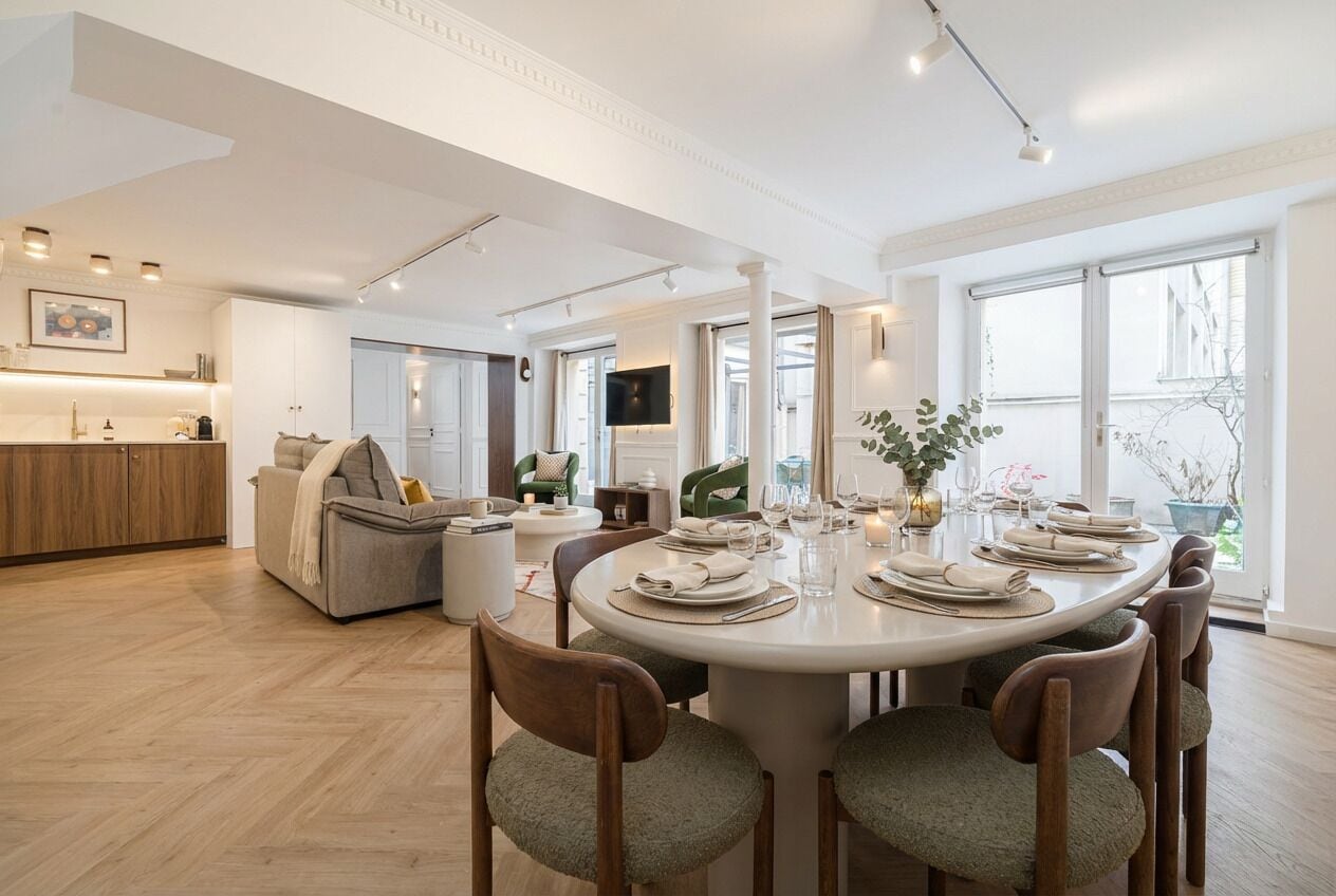 Un comedor moderno con una mesa redonda dispuesta para seis personas, rodeada de sillas de madera con asientos acolchados.