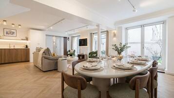 Un comedor moderno con una mesa redonda dispuesta para seis personas, rodeada de sillas de madera con asientos acolchados.