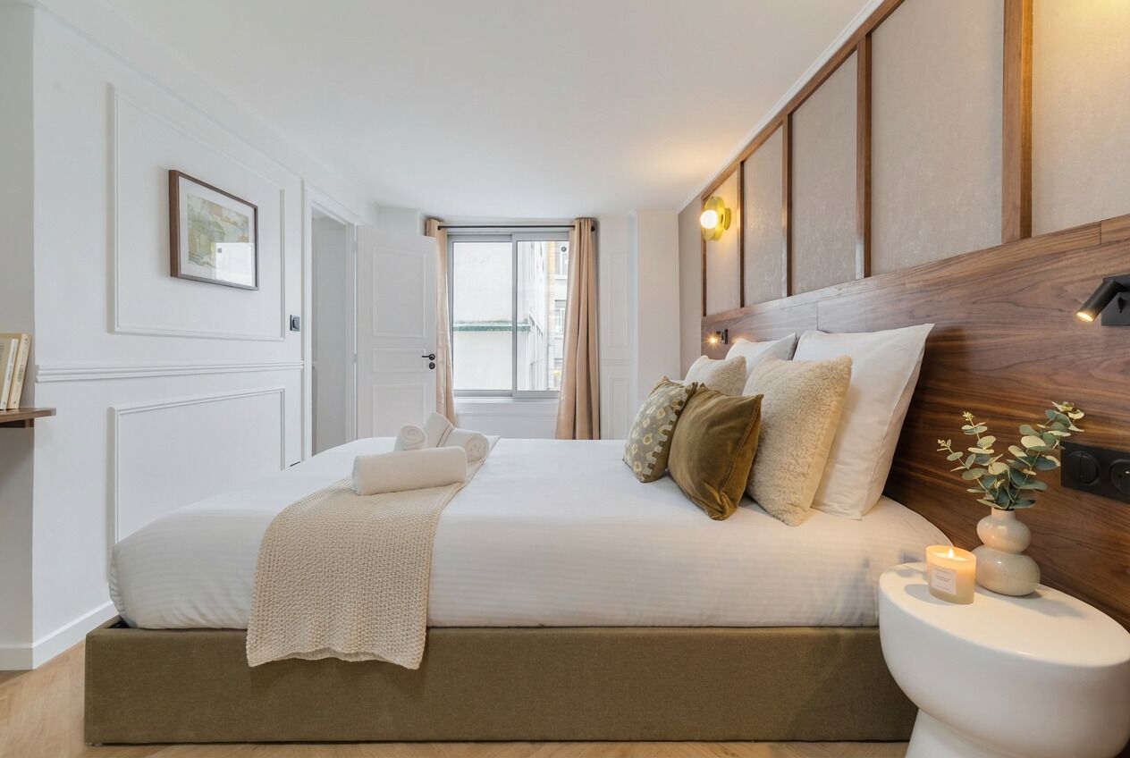 Un dormitorio con cama, mesita de noche y ventana.