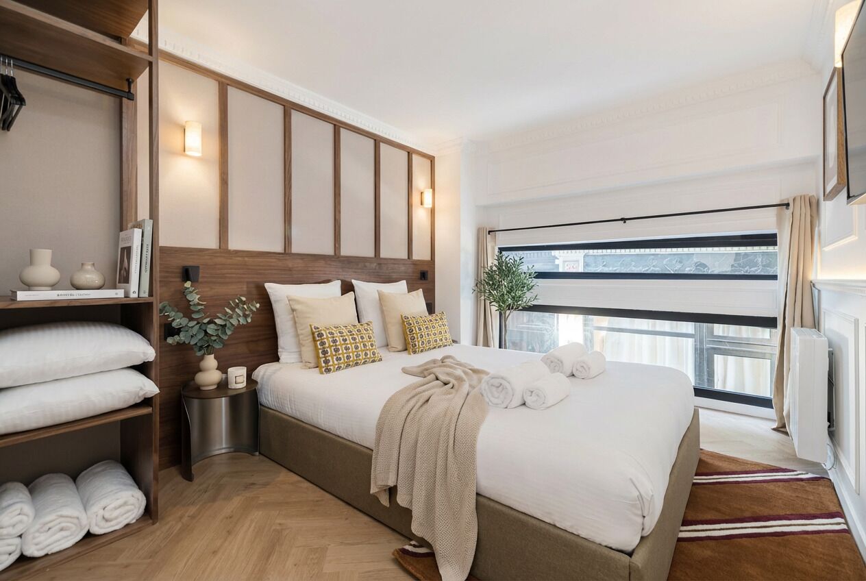 Una habitación de hotel moderna con una cama grande, una mesita de noche, un armario y una ventana con vistas.