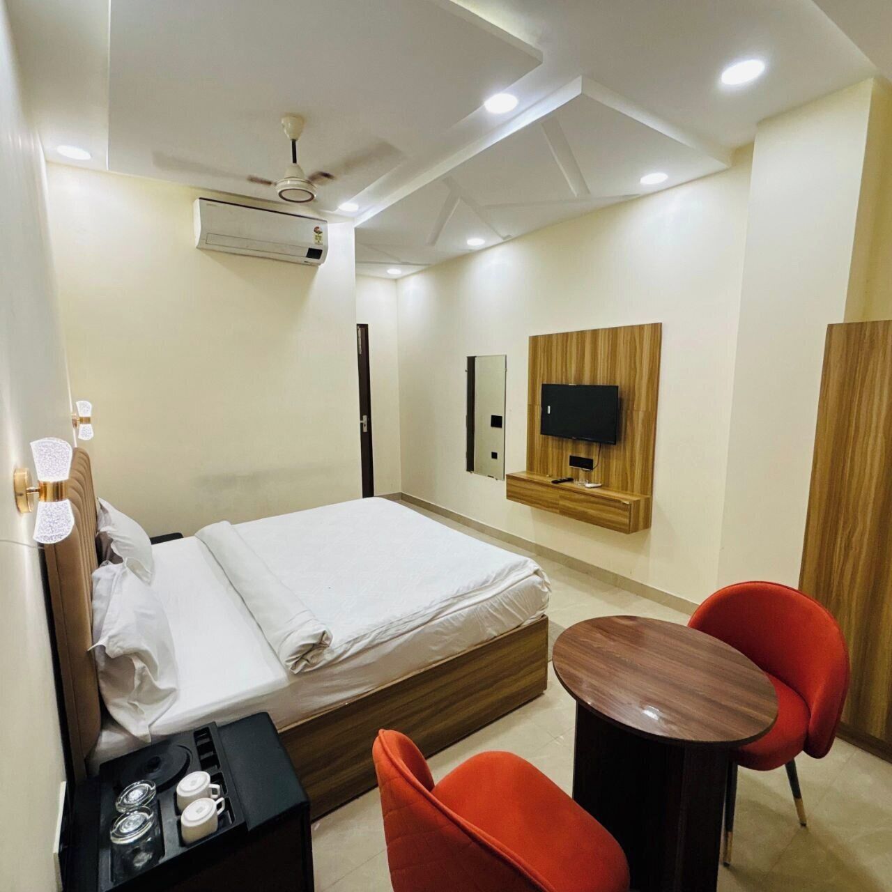 Habitación de hotel con cama, televisor en la pared, una mesita y dos sillas.