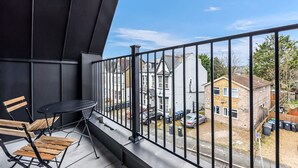 A balcony with a table and chairs, a view of residential buildings, and a clear sky. - Stylish East Croydon Apartment w Balcony Fast Wifi (Croydon)